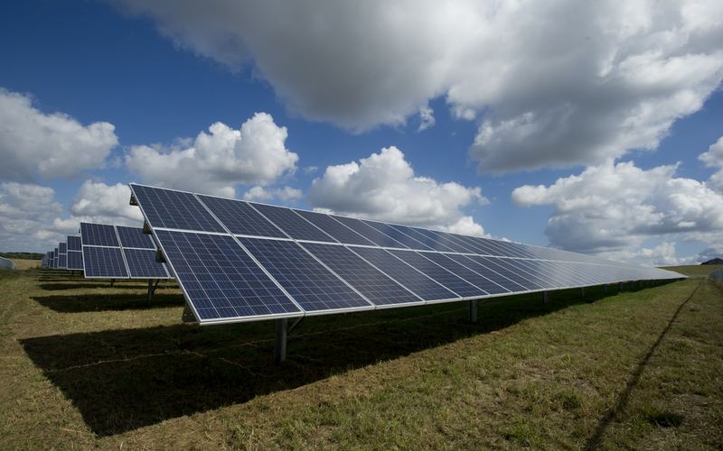 Instalación de generación energética con líneas de transmisión en el atardecer.