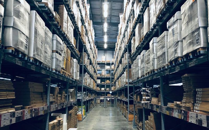 Almacén logístico con estanterías y cintas de clasificación de paquetes.